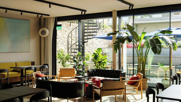A modern interior with a staircase, seating areas, and large windows.