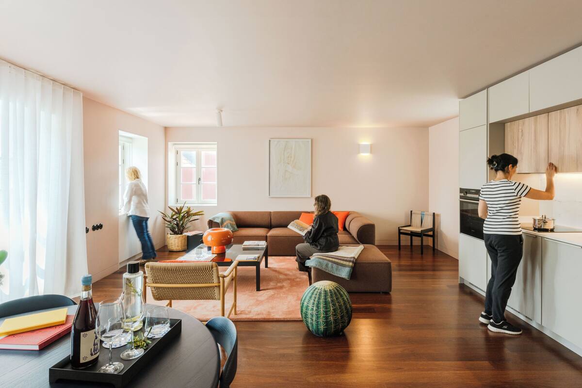 Ett modernt vardagsrum med en soffa, ett soffbord och en matplats med ett bricka fullt av vinglas och en vinflaska.