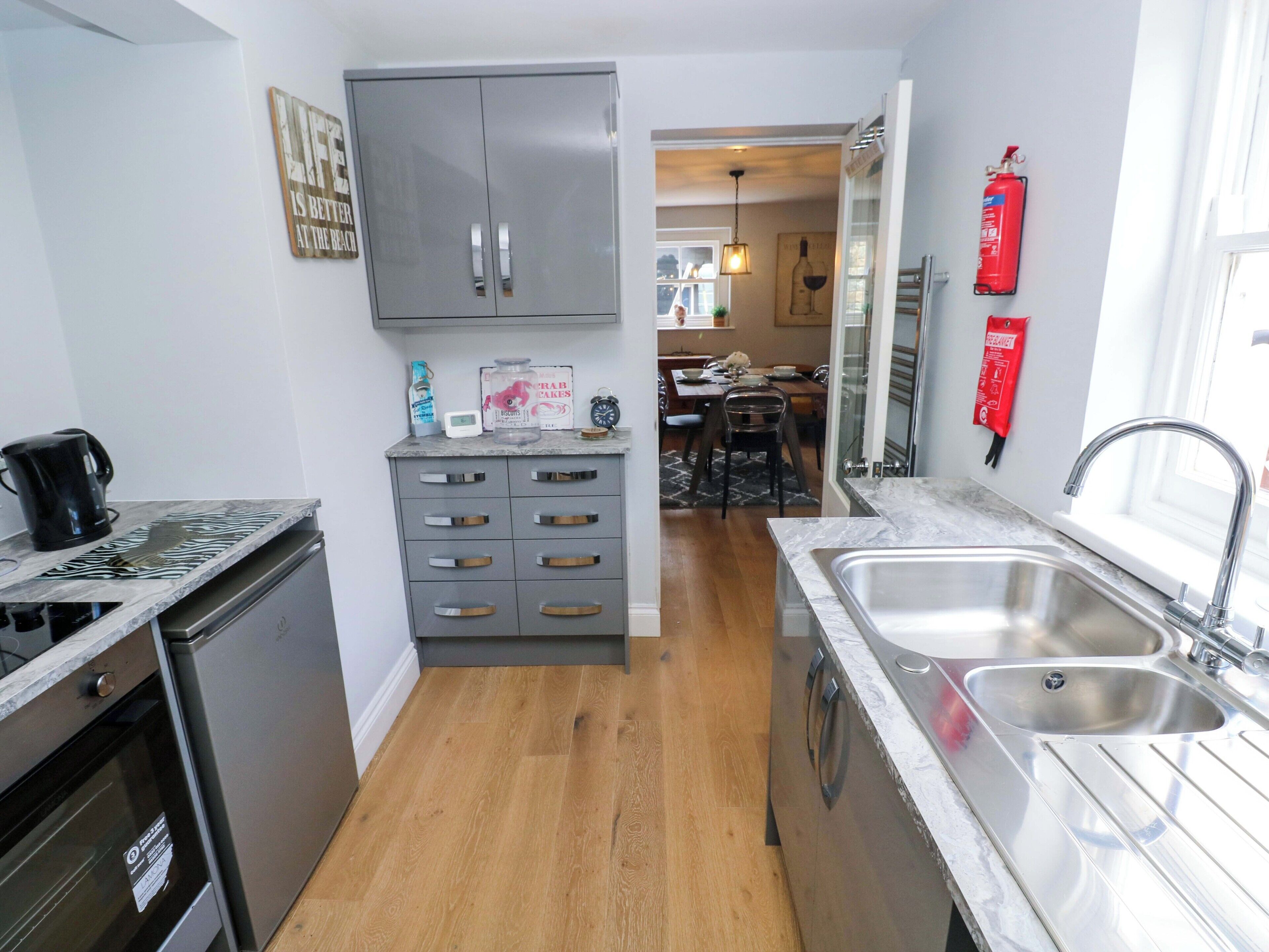 A compact kitchen with a dishwasher, a sink, and a dining area visible in the background.