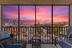 Ein Balkon mit Blick auf eine Stadtlandschaft bei Sonnenuntergang.
