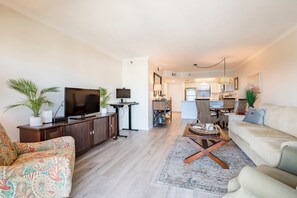 Ein modernes Wohnzimmer mit Flachbildfernseher, einer Couch, einem Couchtisch und einem Essbereich mit Stühlen und einem Tisch.