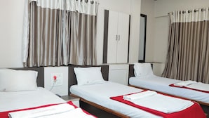 A hotel room with three single beds, each with a red blanket and white pillows. There is a wardrobe with a mirror above the beds, and the room has a neutral color scheme. - Hotel Royal Residency Executive  (Sangli Miraj Kupwad)