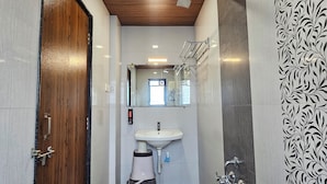 A narrow bathroom with a wooden door, a sink, and a shower.
