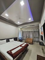 Habitación de hotel con una cama grande, un sofá, un escritorio con silla y un televisor.