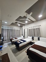 Habitación de hotel con dos camas, un escritorio, una silla, un televisor y un ventilador de techo.