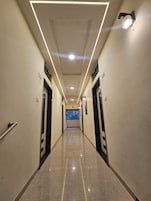 Un pasillo de diseño moderno con un largo corredor, puertas a ambos lados, suelo de baldosas e iluminación empotrada en el techo.
