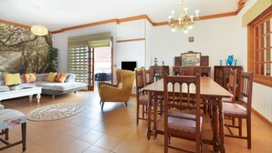 A spacious living room with a dining area, a sofa, a yellow armchair, and a chandelier. - Vacation Chalet Isla Tenerife with Sea Views, Private Terrace and Wi-Fi (Tegueste)