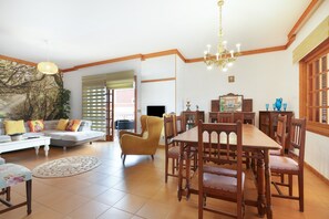 A spacious living room with a dining area, a sofa, a yellow armchair, and a chandelier. - Holiday Villa 'Chalet Tegueste Isla De Tenerife' with Sea Views, Private Terrace & Wi-Fi (Tegueste)