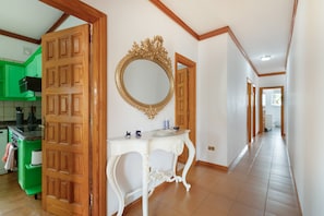 A hallway with a wooden door, a white console table, a gold-framed mirror, and green cabinets. - Holiday Villa 'Chalet Tegueste Isla De Tenerife' with Sea Views, Private Terrace & Wi-Fi (Tegueste)
