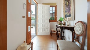 A room with a wooden door, a dining table with chairs, a painting on the wall, and a hat on the floor. - Vacation Chalet Isla Tenerife with Sea Views, Private Terrace and Wi-Fi (Tegueste)