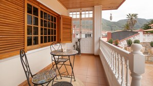 A covered balcony with a table and chairs, wooden shutters, and a view of the surrounding landscape. - Vacation Chalet Isla Tenerife with Sea Views, Private Terrace and Wi-Fi (Tegueste)