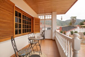 A covered balcony with a table and chairs, wooden shutters, and a view of the surrounding landscape. - Holiday Villa 'Chalet Tegueste Isla De Tenerife' with Sea Views, Private Terrace & Wi-Fi (Tegueste)