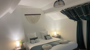 A bedroom with a bed, bedside tables, a hanging light fixture, and a ceiling fan. - Le Gîte des Romains Country house (Anor)