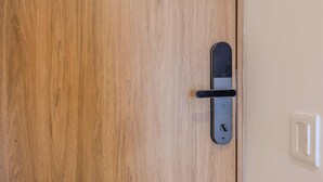 En trædør med en moderne elektronisk lås og en lyskontakt på den tilstødende væg.