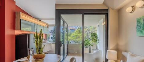 En moderne stue med sofa, spisebord og balkon med udsigt over byen.