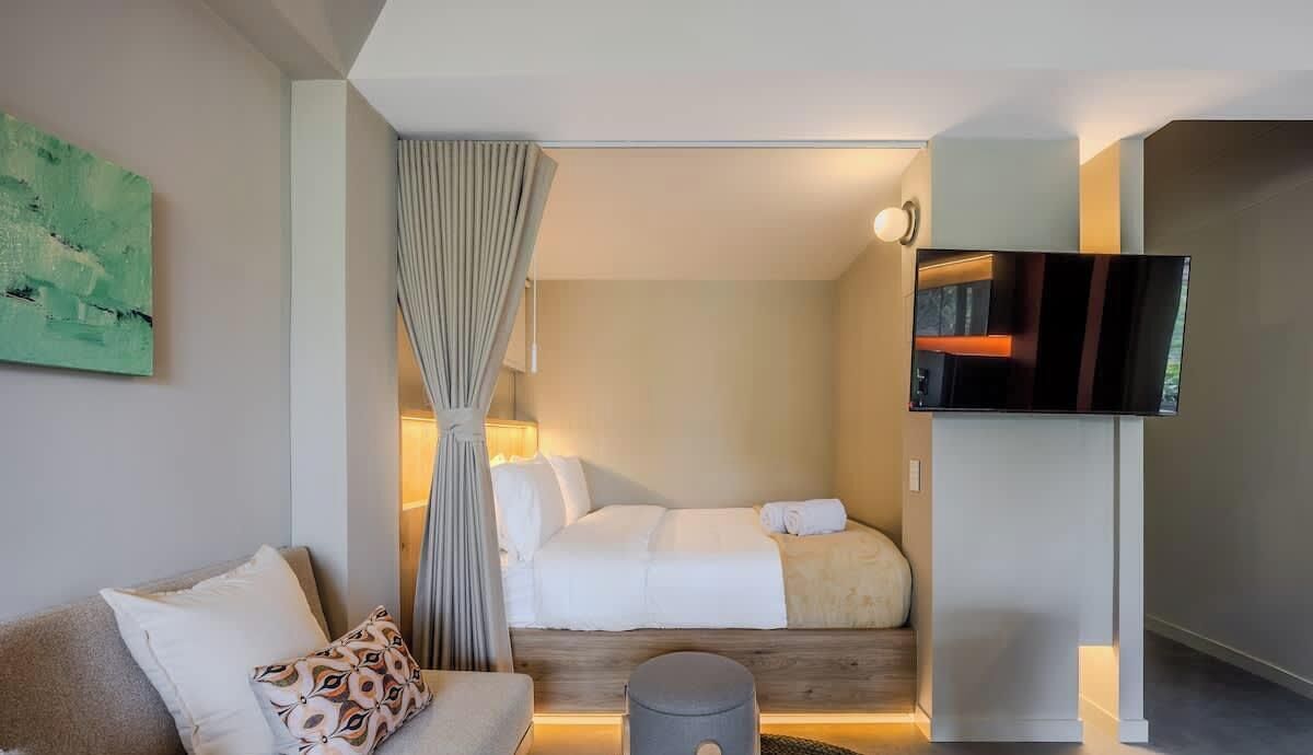 Et hotelværelse med en seng, fjernsyn, sofa og et billede på væggen.