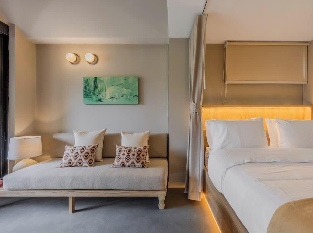 Ein Hotelzimmer mit Bett, Sofa, einem Bild an der Wand und einer Nachttischlampe.
