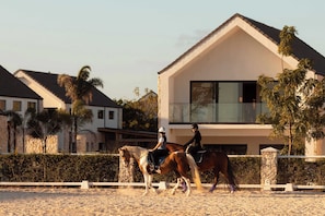 A modern house with a balcony, a horse, and riders. - NOK Luxury 1BR Apartment, The Towers by Vistacana (Punta Cana)