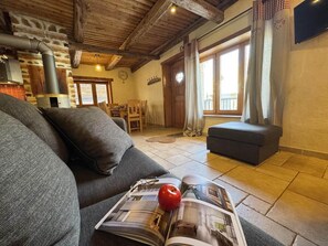 Ein gemütliches Wohnzimmer mit einer Couch, einem Couchtisch mit einer Zeitschrift, einem roten Apfel und einem Kamin.