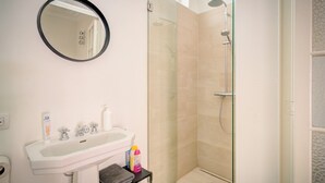 Un baño con lavabo, espejo y cabina de ducha de vidrio.