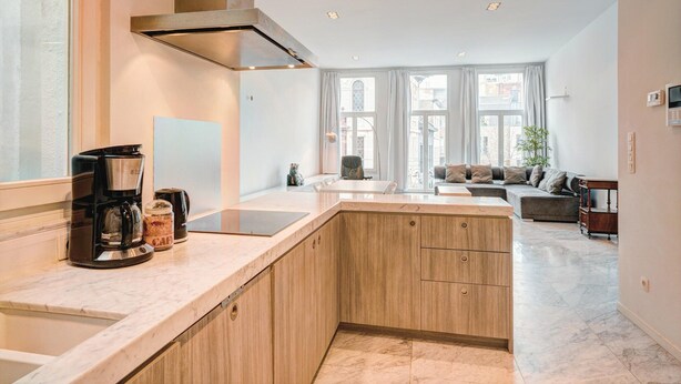 Une cuisine moderne dotée d’un îlot central, de meubles de rangement intégrés et d’une hotte en acier inoxydable.