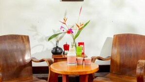 A room with a wooden table, two chairs, a shelf with various items, and a framed picture on the wall. - Double Room with Garden View (Hà Nội)