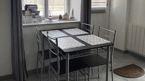 Et spiseområde med et bord, stole, et vindue med gardiner og en radiator på væggen.