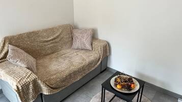 En moderne stue med en grå sofa, mønstrede hynder og et lille sort sofabord med en dekorativ anretning.