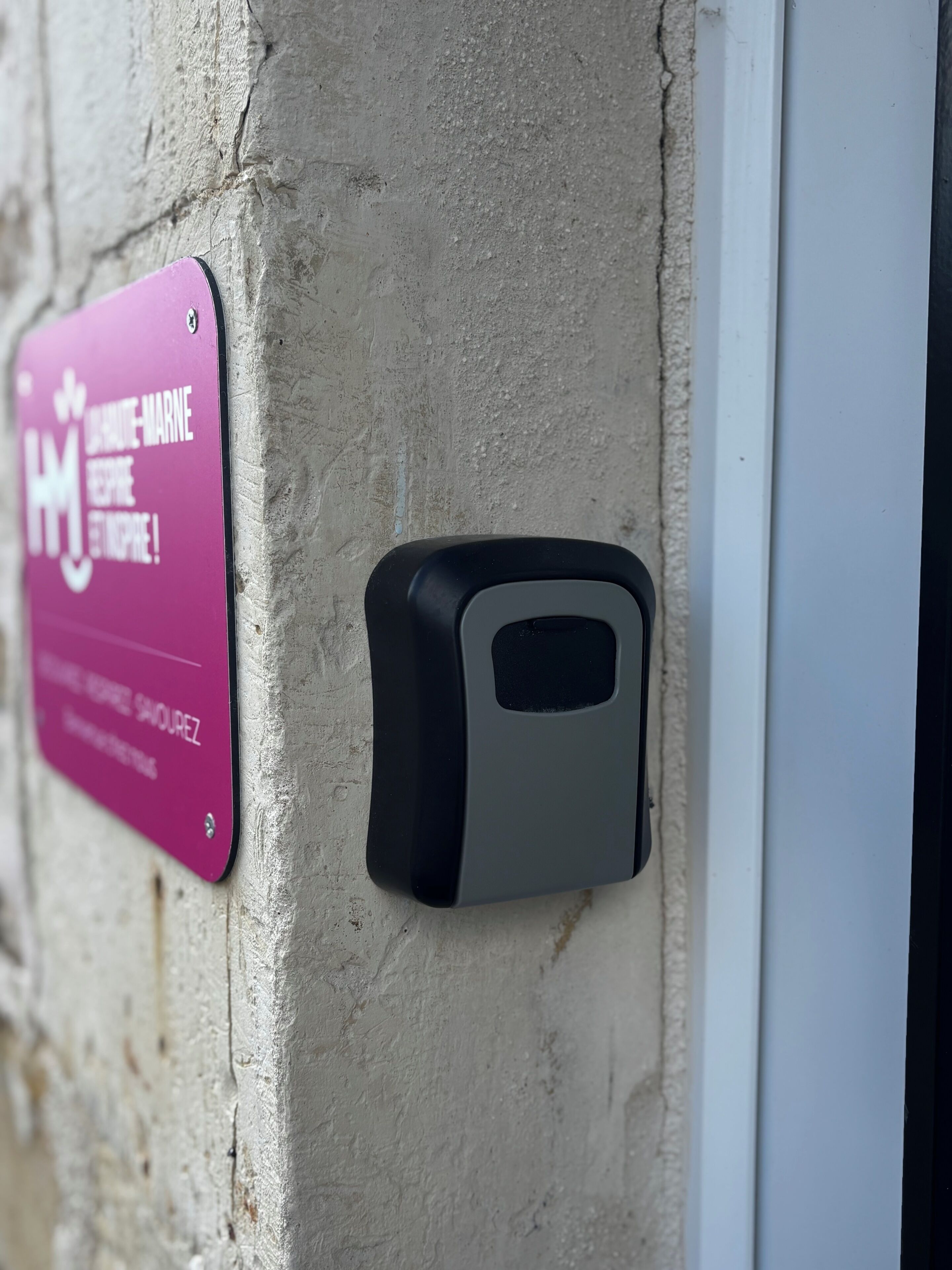 Un interphone fixé au mur et une plaque avec du texte.