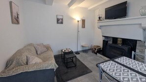 En stue med sofa, lille bord, gulvlampe, pejs og fjernsyn.
