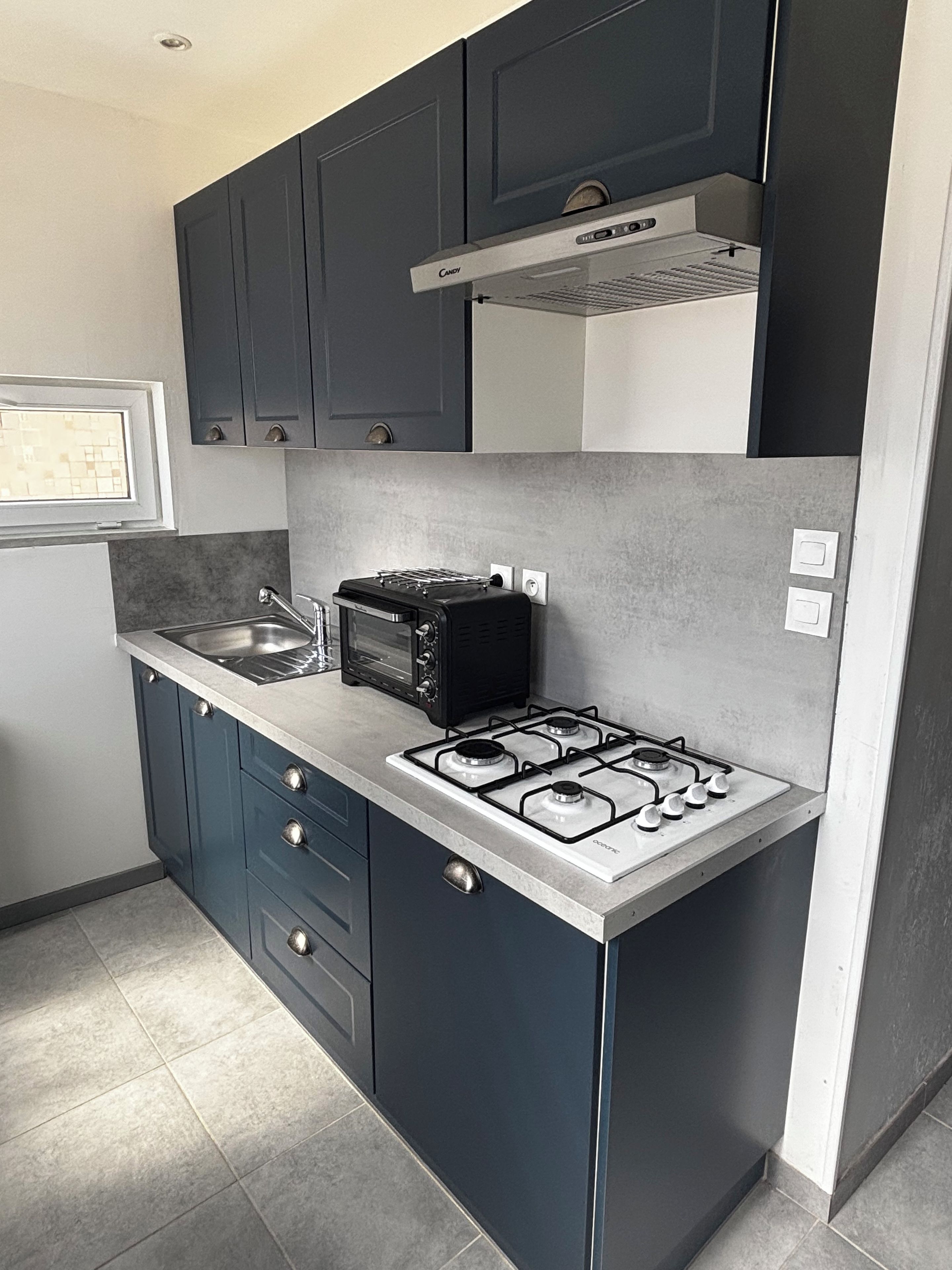 A modern kitchen with dark cabinets, a gas stove, a microwave, and a toaster.