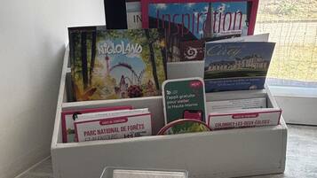Une pile de brochures de voyage et une carte de visite sont posées sur une table près d’une fenêtre.