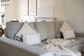 Ein graues Sofa mit weißen Kissen und einer Strickdecke.