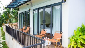 A balcony with chairs, a table, and a glass door leading to a room.