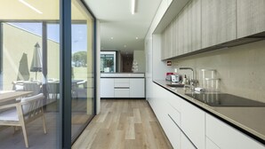 Una cocina moderna con armarios blancos, encimera negra y una zona de comedor con mobiliario de madera.