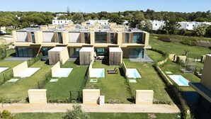 Un moderno complejo residencial con varias unidades, un patio central con asientos y una piscina.