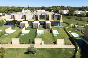 A modern residential complex with multiple units, a central courtyard with seating, and a swimming pool. - Vilamoura Parque - Luxury Villa with pool by HD (Vilamoura)