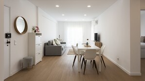 A modern apartment with a dining area, a sofa, a TV, and a mirror.