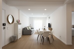 Ein modernes Apartment mit Essbereich, einer Couch, einem Fernseher und einem Spiegel.