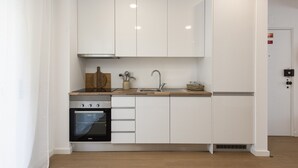 A compact kitchen with white cabinetry, a built-in oven, and a sink.