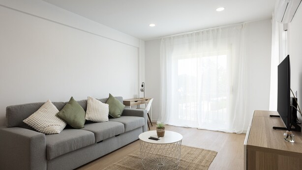 A modern living room with a grey sofa, a round coffee table, and a TV on a wooden stand.