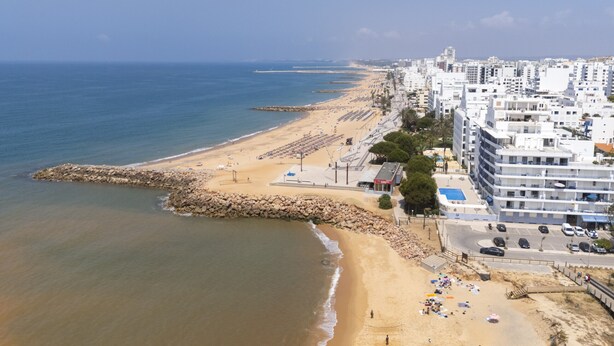 Eine Küstenstadt mit Strand, Gebäuden und einem Felssturm.