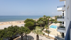 Ein Hotel direkt am Strand mit Pool, Palmen und Meerblick.