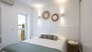 Une chambre à coucher comprenant un lit, une fenêtre, un luminaire fixé au mur et un élément décoratif mural.