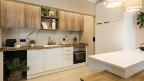 Een moderne keuken met houten kastjes, een marmeren spatwand, een ingebouwde oven en hanglampen.