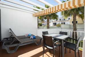 Un patio exterior con una mesa y sillas, una tumbona y una mesa de billar.