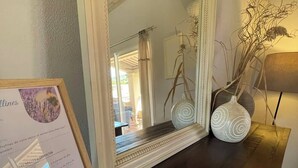 Un espejo con un marco decorativo, una mesa de madera oscura y dos jarrones blancos con un diseño en espiral.