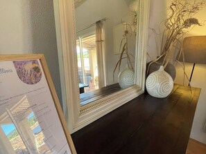 A mirror with a decorative frame, a dark wooden table, and two white vases with a spiral design. - Gîte "Le Rosé du Ventoux" (4 pers) (Méthamis)