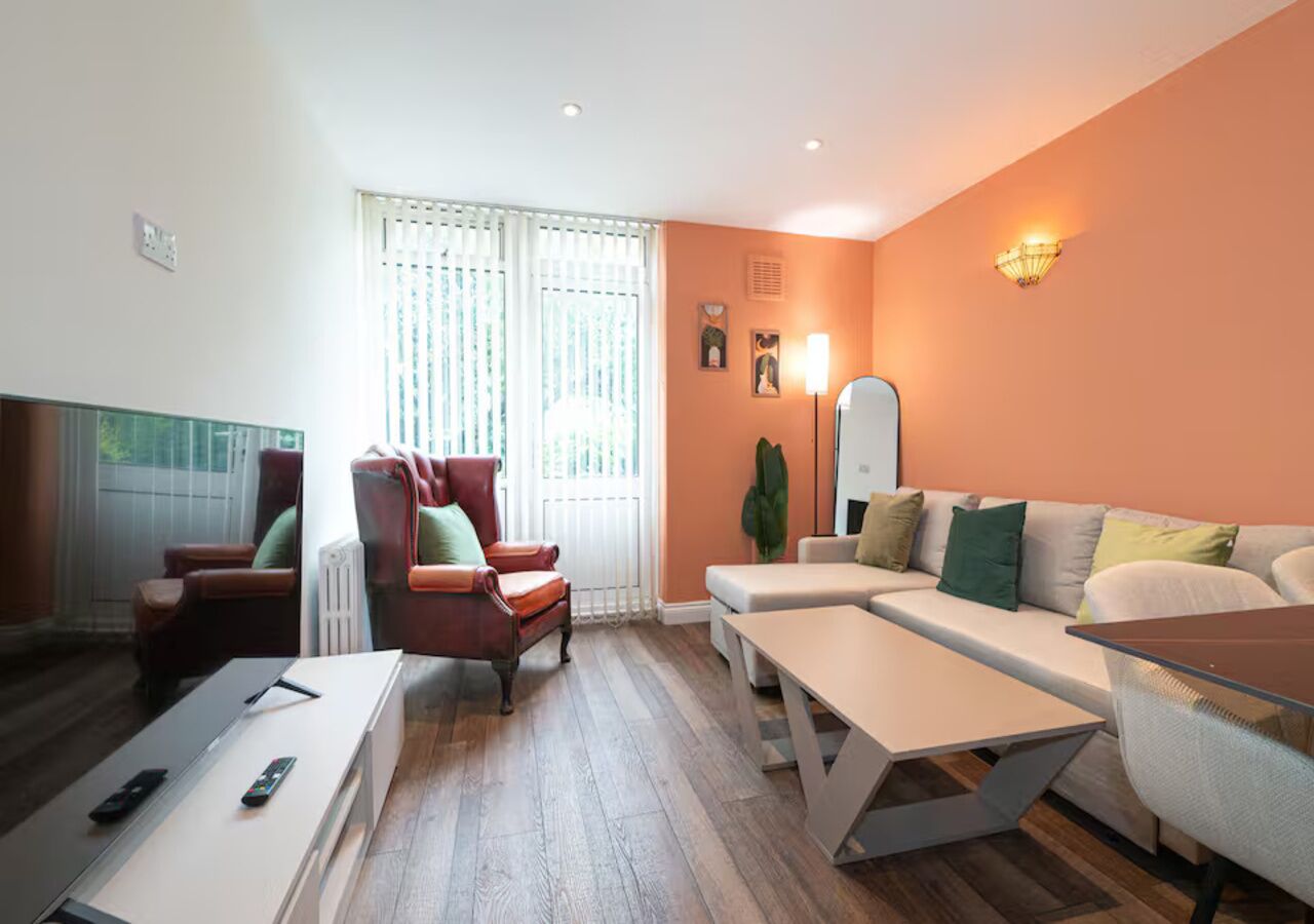 Ein modernes Wohnzimmer mit einer Couch, Sesseln, einem Couchtisch und einem Fernseher.