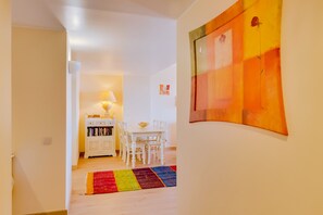 A hallway leading to a dining area with a table and chairs, a bookshelf, and a colorful rug. - São Vicente - Vilamoura (Vilamoura)